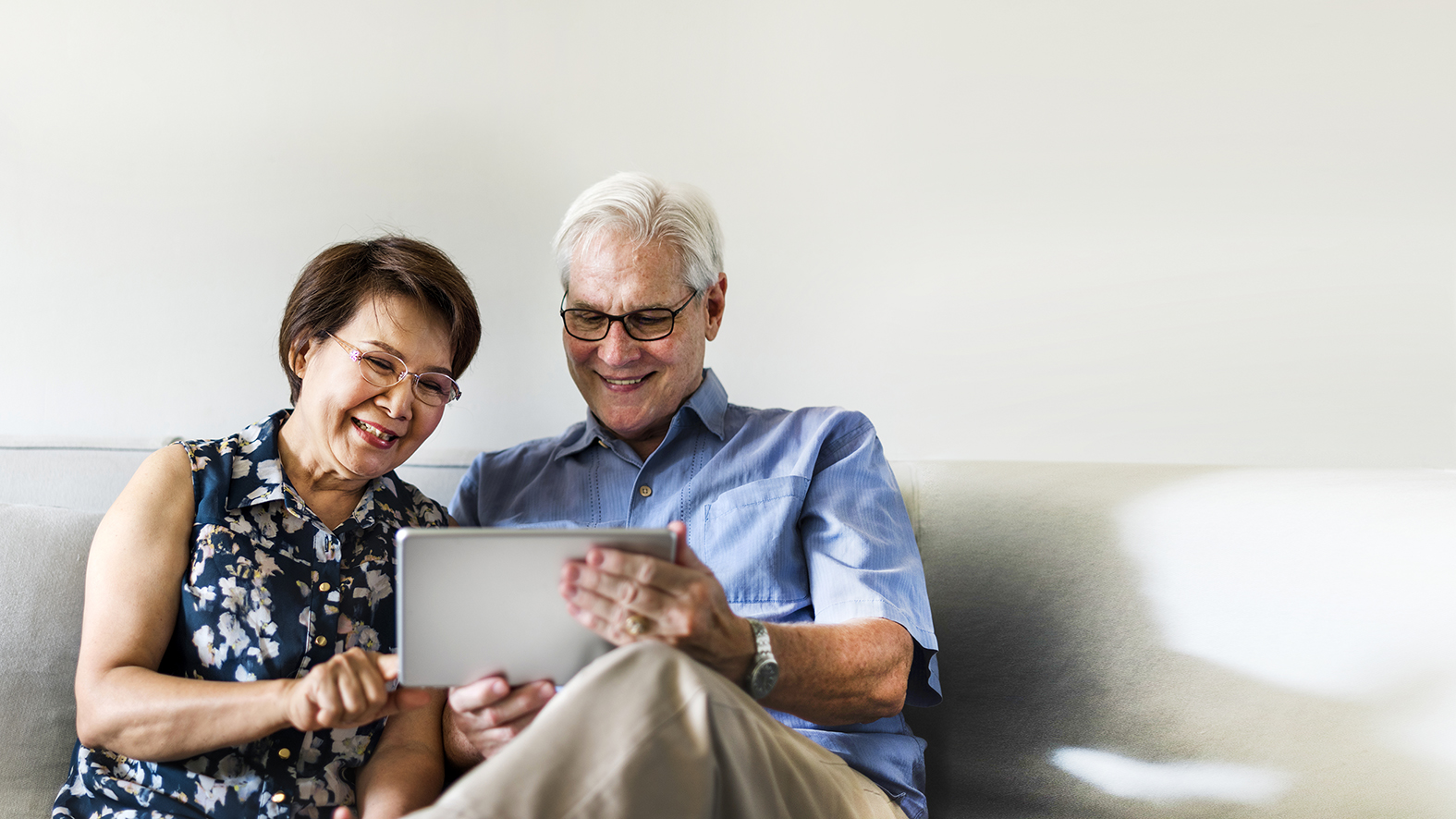 Senior couple using a digital device in a living room